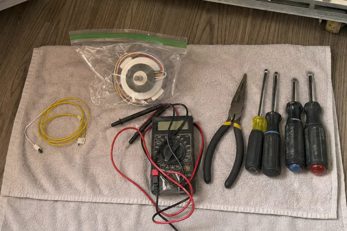 A tidy row of drivers and pliers on a work towel laid over a kitchen floor