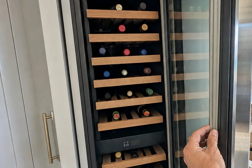 The upper racks of a wine column seen through the glass, bottles resting on their sides under the interior light