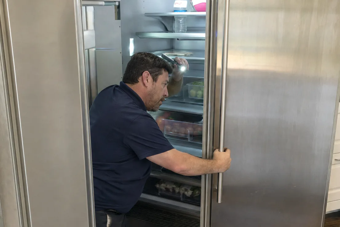 The refrigerator half of a built-in standing open, its own evaporator compartment visible behind the shelves